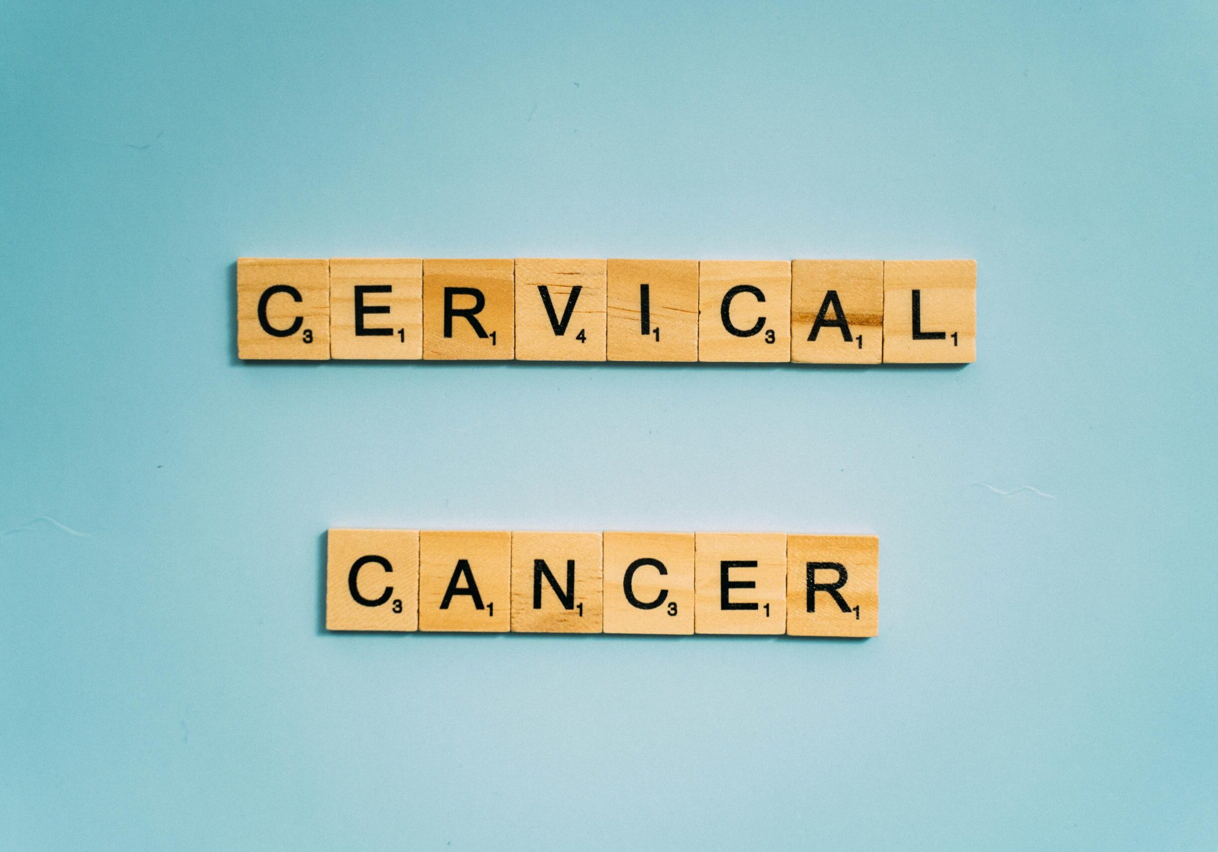Scrabble tiles spelling 'Cervical Cancer' on a light blue background for awareness.